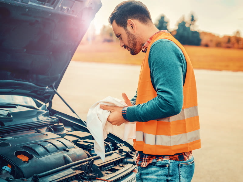 Mobile mechanic in a high-visibility vest working on a car at the roadside