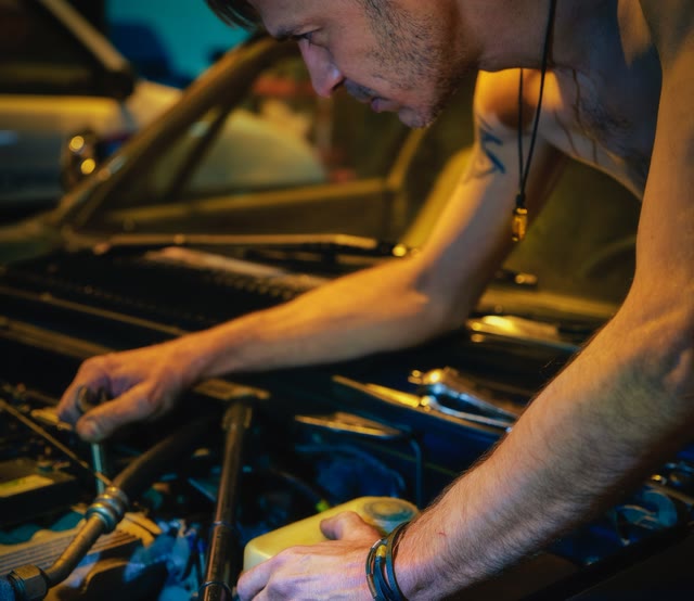 Mechanic leaning into a warmly lit engine bay